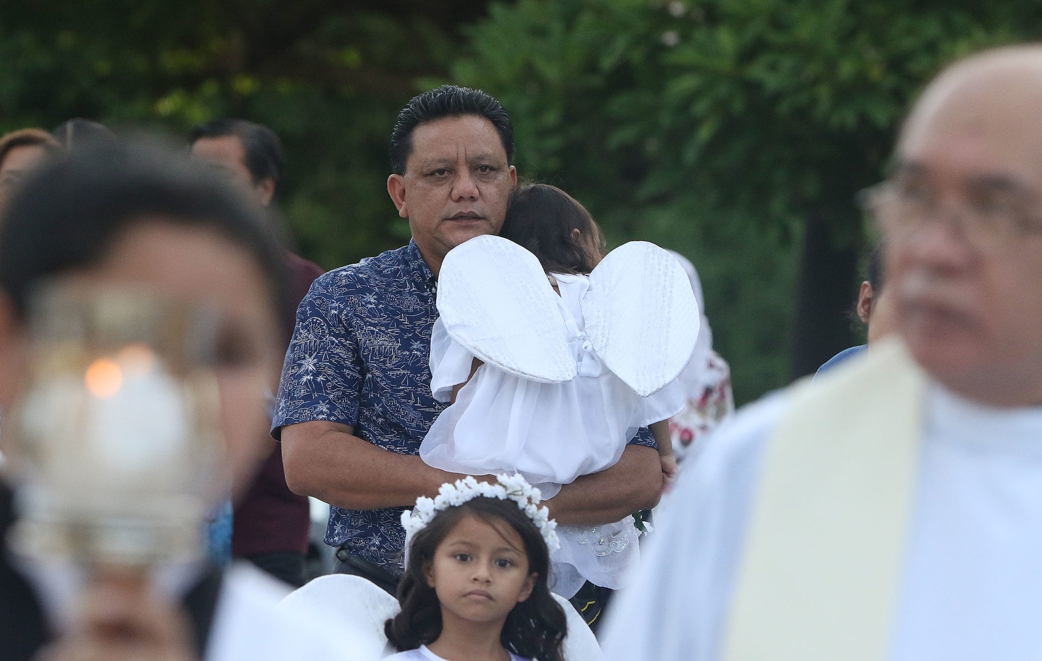 Roland Sandia carries his grand daughter in the procession held at Assumption of Our Lady Biba Santa Maria fiesta. Sandia alleges Archbishop Apuron sexually abused he and other altar servers