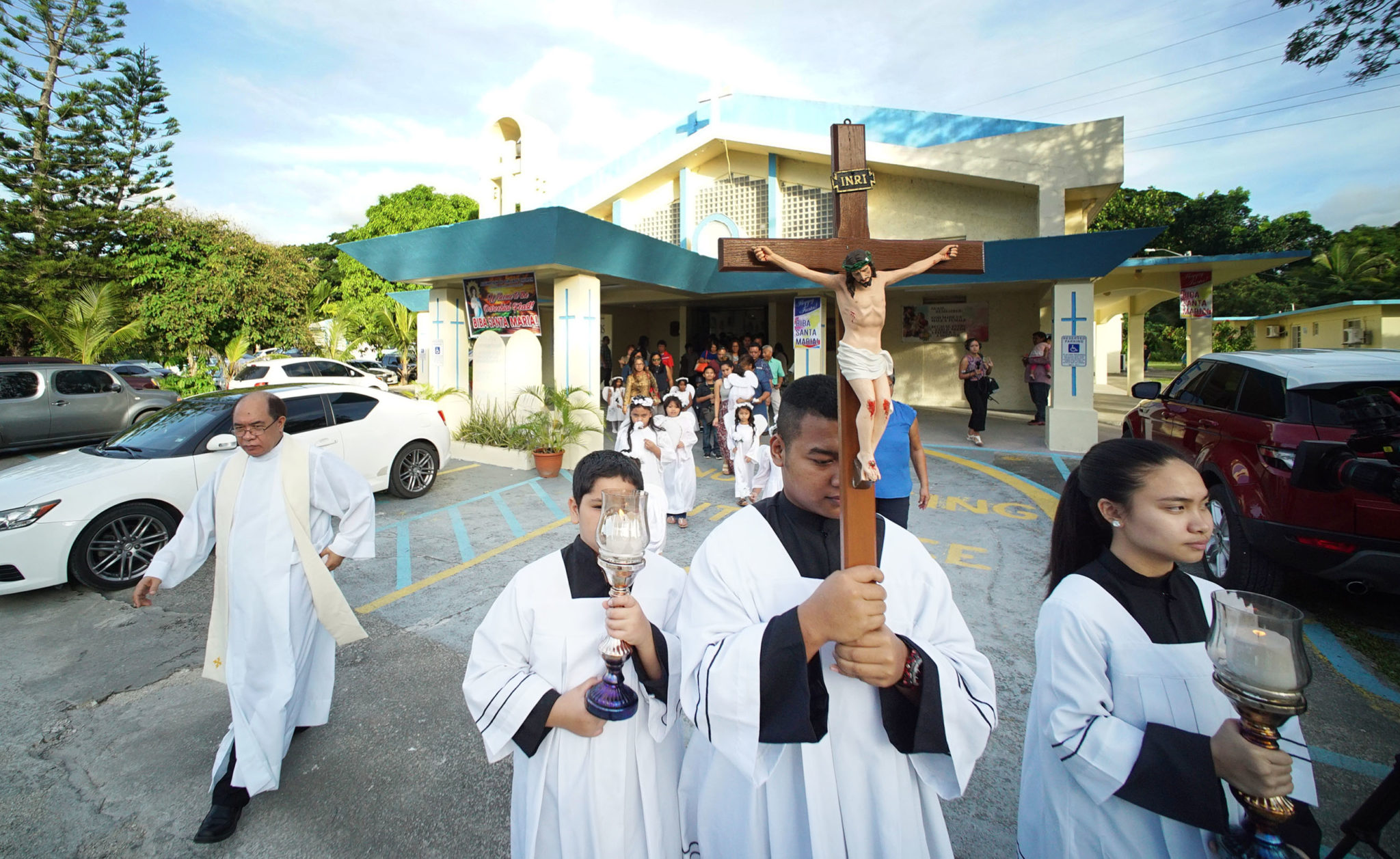 Left, Father Mel Camina leads processional out of the Assumption of Our Lady in Piti, Guam during processional.