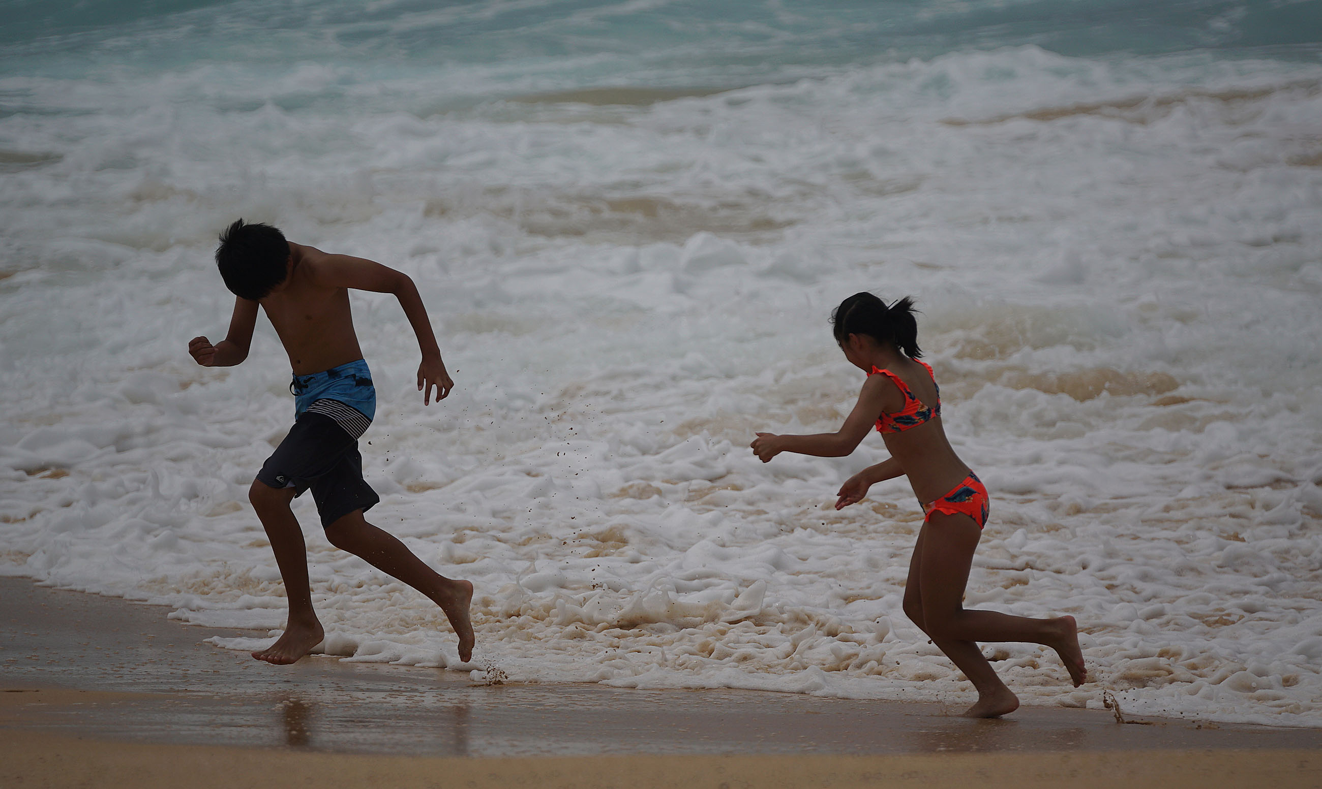 Kids play near dangerous shorebreak at Sandy Beach.